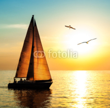 Obrazy i plakaty Yacht sailing against sunset with seagulls