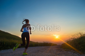Naklejki woman running on a mountain road at summer sunset