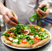 Obrazy i plakaty Closeup hand of chef baker in white uniform making pizza at kitc