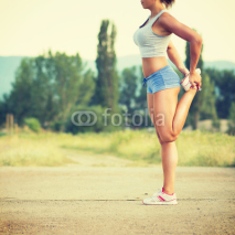 Obrazy i plakaty Fit young woman stretching her leg after jogging