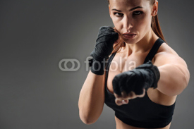 Joyful woman boxing on a grey background
