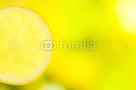 Naklejki slice of lemon on green and yellow background
