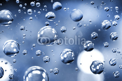 Close-up on water drops background on glass blue surface. Water droplets with reflections in them.