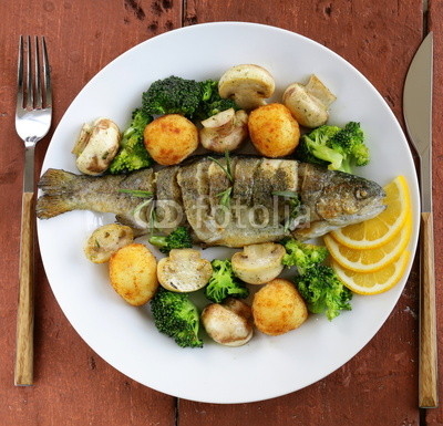 roasted trout fish with vegetables and lemon on a plate
