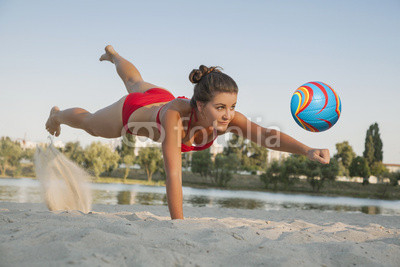 Young beautiful lady is playing volleyball on the beach