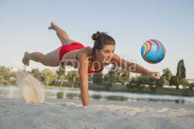 Obrazy i plakaty Young beautiful lady is playing volleyball on the beach