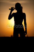 silhouette of a young sportive woman drinking water
