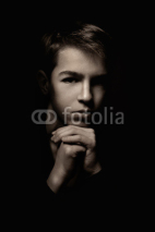 Fototapety Portrait of pensive teenager on black background