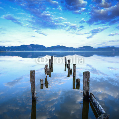 Wooden pier or jetty remains on a lake sunset. Tuscany, Italy