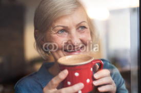 Senior woman at the window holding a cup of coffee