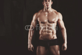 Fototapety Close up of young muscular man lifting weights over dark background