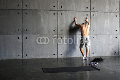 Man at the wall in the gym resting after exercise