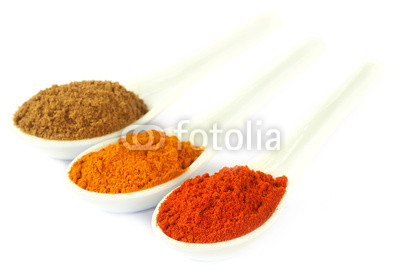 Some ground spices on white spoons