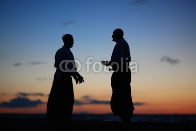 Silhouettes of two men speaking at sunset