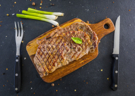 Naklejki Grilled beef steak served on a wooden board.