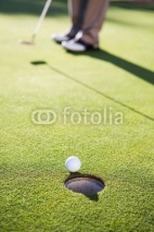 Naklejki Golfer putting ball on the green