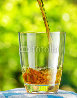 Glass of apple juice on nature background