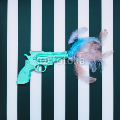 blue plastic gun from which fly the feathers of a bird