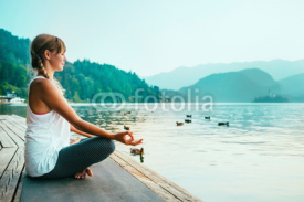 Meditation. Young woman meditating by the lake.