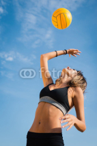 Naklejki Jumping beach volleyball female player serving ball.