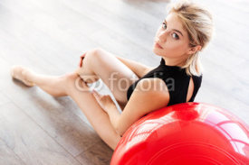 Naklejki Fitness woman sitting on the floor with red fitball