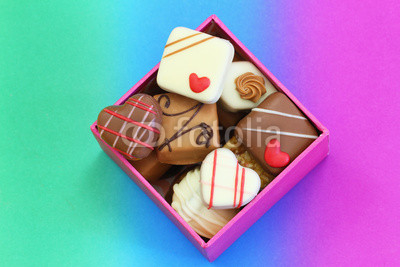Assorted chocolates in box on colorful background