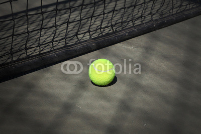 Tennis ball on the court with the net on the background