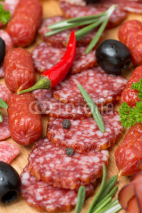 Fototapety Assorted meats and sausages on a wooden board, close-up