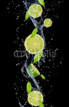 Fototapety Limes in water splash, isolated on black background
