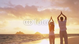 Yoga, fitness, sport, and wellness lifestyle concept. Couple doing yoga exercises on beach from back at sunrise on serene peaceful beach. Relaxation and yoga meditation on Lanikai, Oahu, Hawaii