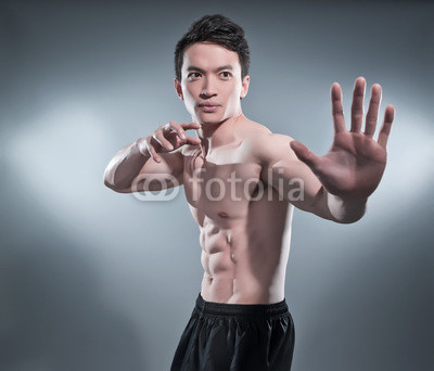 Muscled asian kung fu man in action pose. Blood stripes on his c