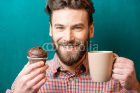 Close-up portrait of a man with chocolate muffin and coffee cup on the green background