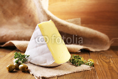 Tasty Camembert cheese with thyme and olives, on wooden table