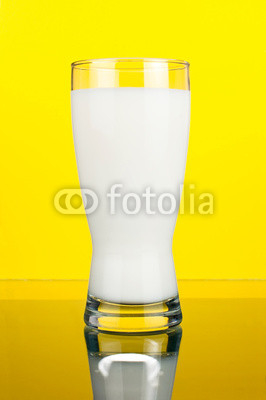 Glass of fresh milk on a dark yellow background