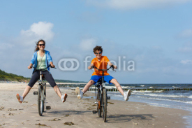Fototapety Teenage girl and boy biking on beach