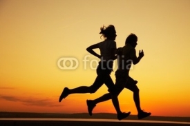 Naklejki Young couple run together on a sunset