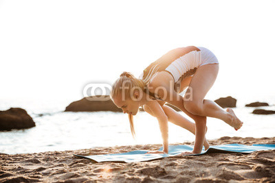 Beautiful young woman balancing on hands and practicing yoga