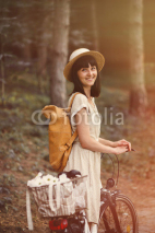 Naklejki Girl on a bicycle in coniferous forest. Lightleak effect and ins