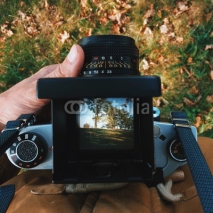 Obrazy i plakaty man photographer is making  landscape photography with old film camera