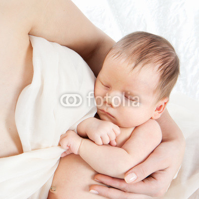 Newborn baby lying on hands of his mother