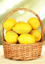 Fototapety Ripe lemons in wicker basket on table on bright background