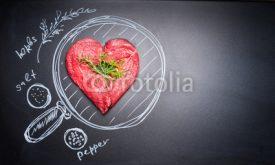 Naklejki Heart shaped chop of meat on black chalkboard with  painted pan and ingredients, top view, place for text. For Meat lovers and eater