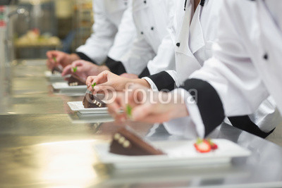 Team of chefs garnishing dessert plates