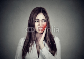 woman with sensitive toothache suffering from pain touching outside mouth .