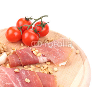 Prosciutto with tomatoes on wooden platter.