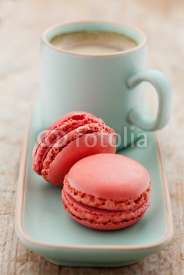 Cup of coffee and macaroons on wooden table, toned