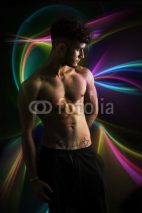 Young shirtless man over dark colorful background