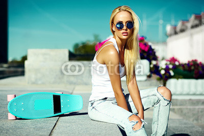 High fashion look.glamor stylish sexy beautiful young blond  model girl in summer bright casual hipster clothes with skateboard behind blue sky in the street