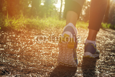 Athlete runner feet running in nature, closeup on shoe. Woman fitness jogging, active lifestyle concept