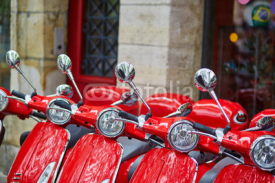 Red retro scooters parked on a Parisian street